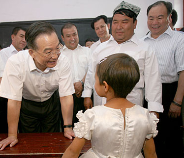 Chinese Premier Wen Jiabao (L) talks with a student at a bilingual kindergarten during his inspection tour to the northwestern Xinjiang Uygur Autonomous Region from last Thursday to Sunday. Wen Jiabao visited villages, schools, enterprises, hospitals and the Xinjiang production and construction corps of the army in a number of prefectures and cities to show his extensive care for local people's livelihood, education, medical service and the development of energy sources，Xinhua reported.Picture taken on August 16.[Xinhua]