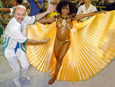 Well-known Samba dancer Valeria Valensa (R) is escorted by her husband Hans Donner during the parade by Academicos do Tucuruvi samba school in Sao Paulo, February 5, 2005. Brazilians of all walks of life sang and danced during the annual Carnival festivities.
