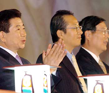 South Korean President Roh Moo-hyun (L) applauds next to convention's chairman Yuan Kuo-Tung (C) and Huang Meng Fu (R), Chairman of the All-China Federation of Industry and Commerce, during the opening ceremony of the 8th World Chinese Entrepreneurs Convention in Seoul, October 10, 2005.