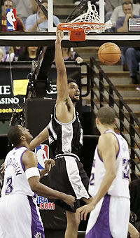 an Antonio Spurs Tim Duncan (C) dunks the ball past Sacramento Kings Shareef Abdur-Rahim (L) and Francisco Garcia in the first half of NBA action in Sacramento, California November 21, 2005.