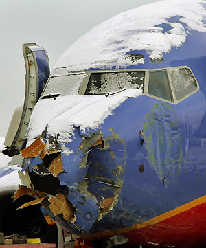 jWorkers survey the Southwest Airlines plane as it sits on a truck after being removed from a busy street bordering Chicago's Midway Airport December 10, 2005. The plane skidded off a snowy runway and onto adjacent streets during a snowstorm on Thursday evening, killing a child riding in a car and came to rest atop two vehicles in the road.